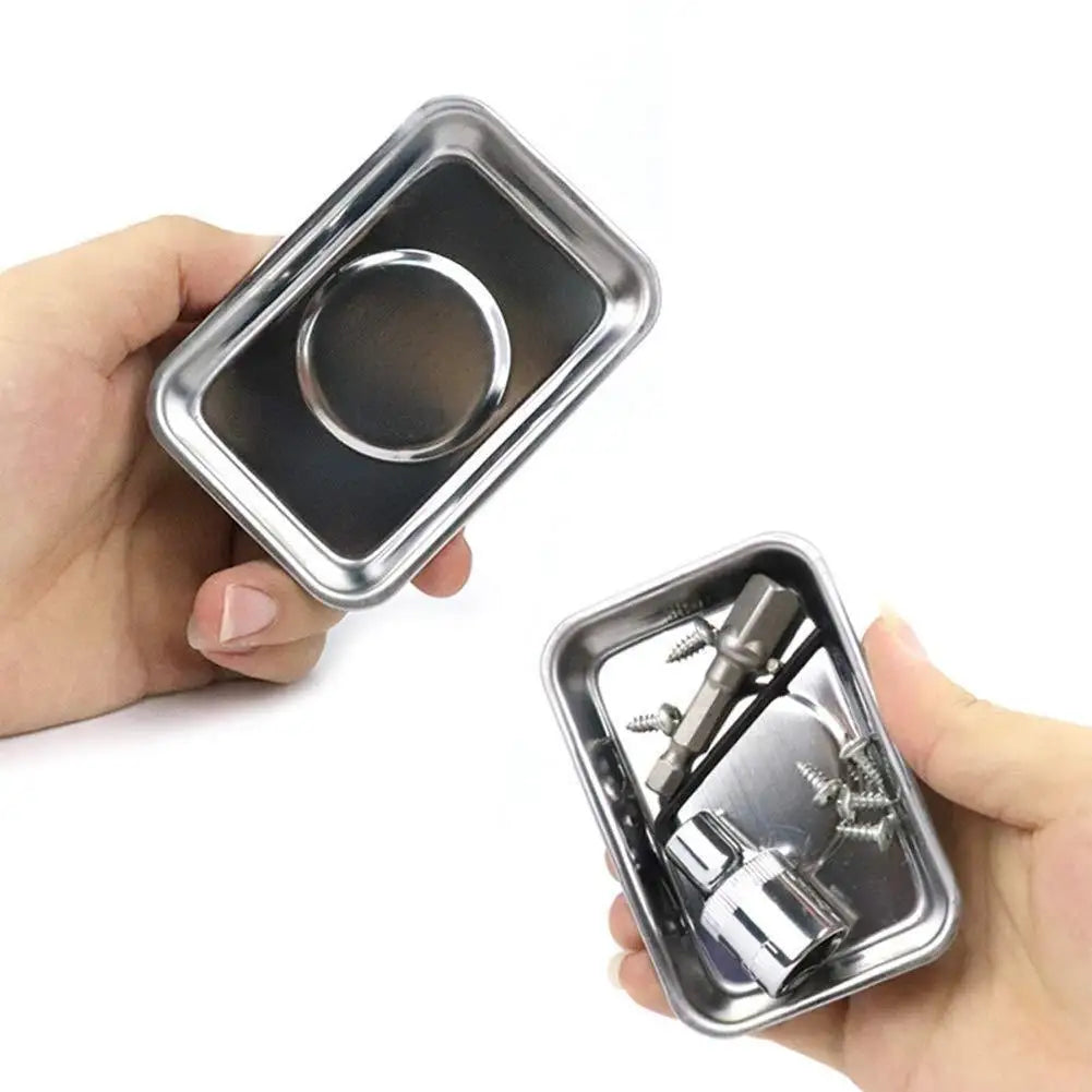 Eine Hand hält einen silbernen magnetischen Teile-Organizer mit kreisförmiger Öffnung und kleinen Werkzeugen darin.