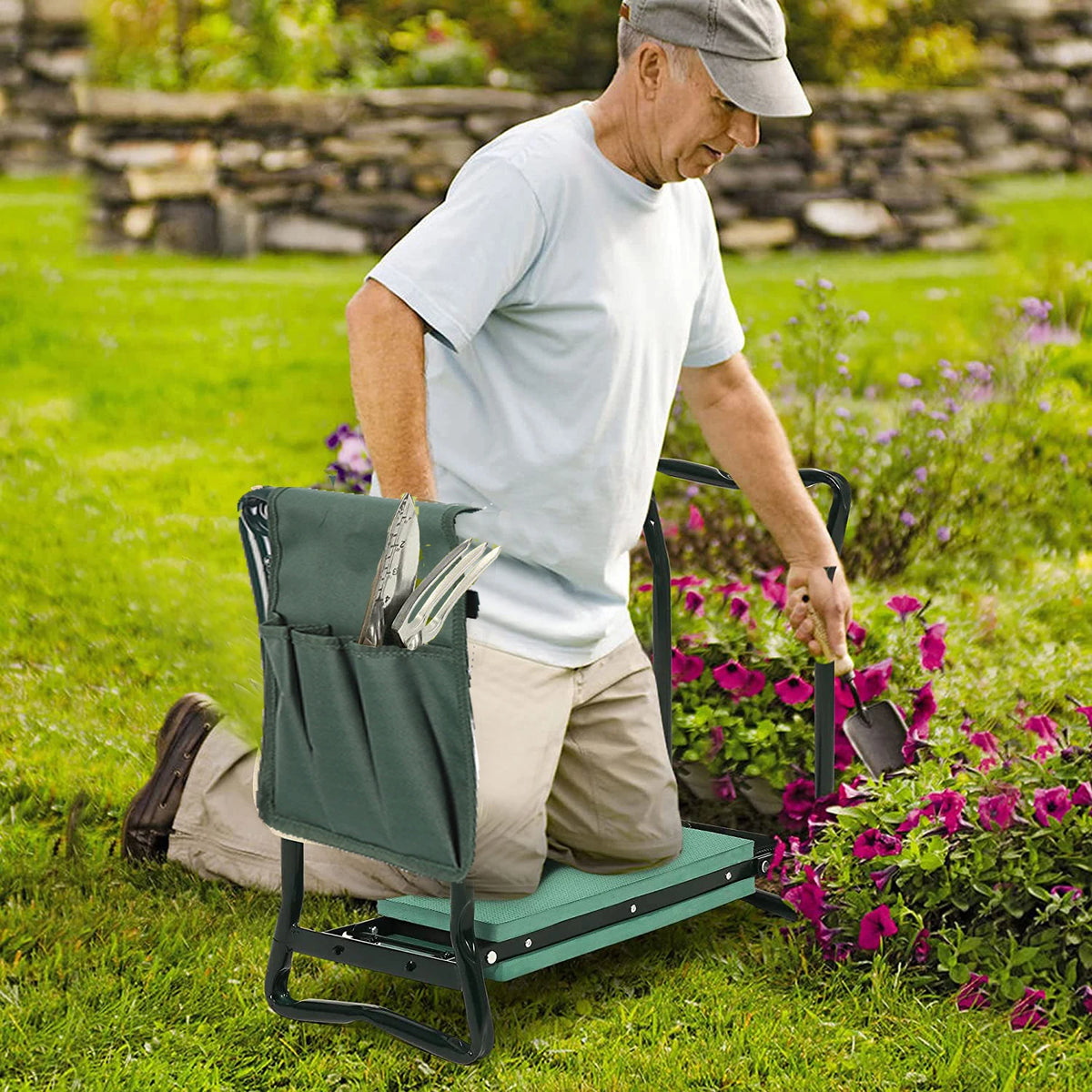 Ein älterer Mann kniet auf einem schweren Gartenhocker in einem grünen Garten umgeben von blühenden Pflanzen.