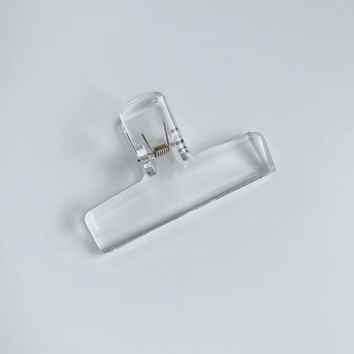 Klares Acryl-Federklammer mit flachem Körper und Federmechanismus.
