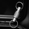 A close-up shot of a titanium alloy rotating keychain key holder attached to a dark surface.