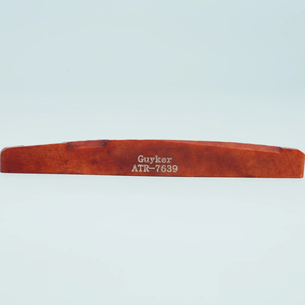 A wooden guitar bridge saddle with the name Guyker and model number ATR-7639 engraved on it.
