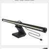 An adjustable black LED light bar with multiple bright white LEDs is shown on a desk setup.