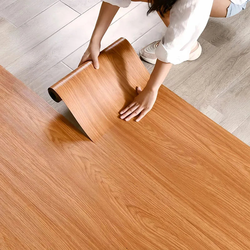 A person is applying wood grain self-adhesive wall stickers onto a wooden surface.
