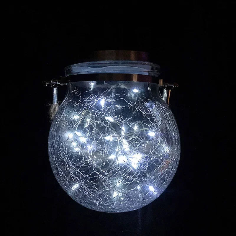 Kugelförmige Rissglas-Solarlaterne leuchtet hell vor dunklem Hintergrund.