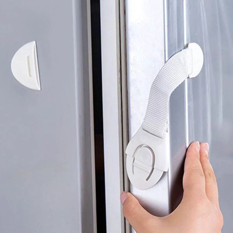 A hand is using a silicone safety clip to open a door or drawer.