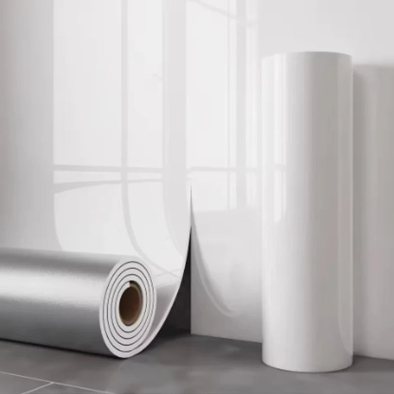 Rouleau d'autocollants imitation marbre blanc auto-adhésifs, à côté d'un mur blanc.