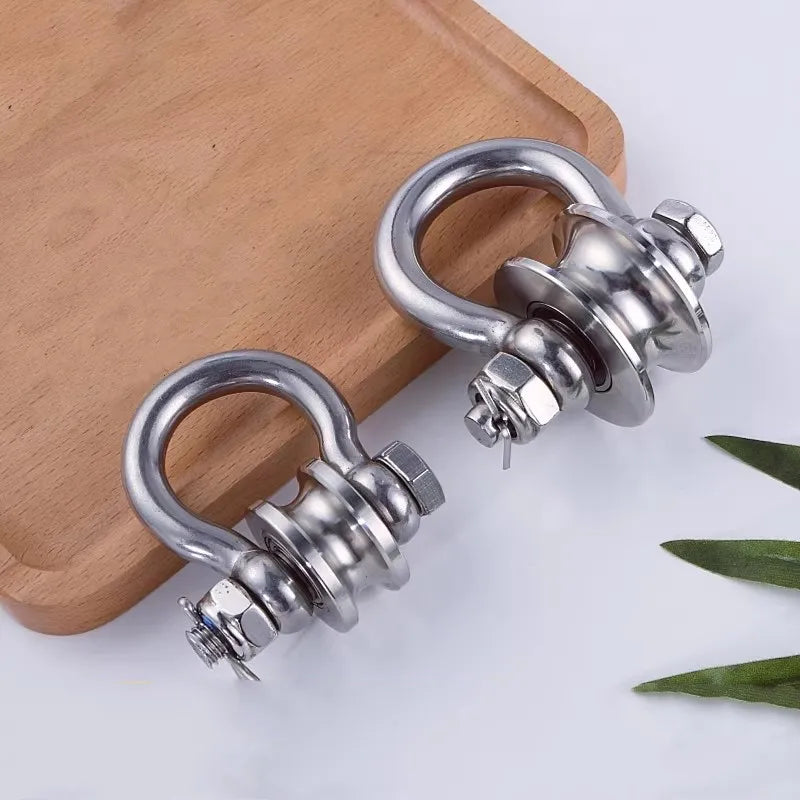 A heavy-duty stainless steel buckle pulley is shown resting on a wooden surface.