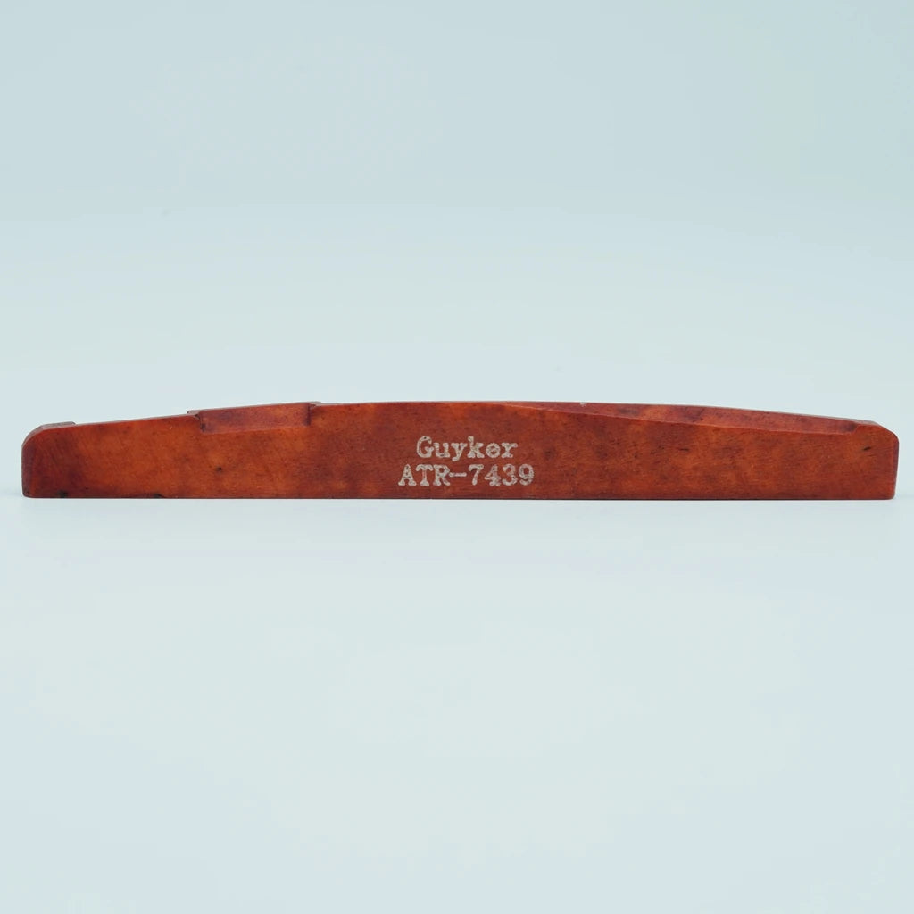 A wooden guitar bone bridge saddle labeled Guyker ATR-7439