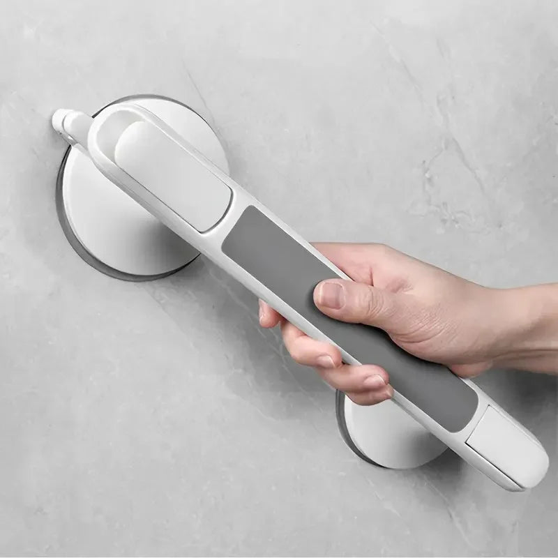 A hand is holding a white and gray suction cup grab bar designed for elderly safety.