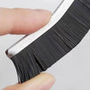 A hand holds a black and silver grout gap cleaning brush set with fine bristles.