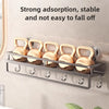 A silver wall shelf holds five gold-colored shower caddy organizers designed for strong, stable grip.