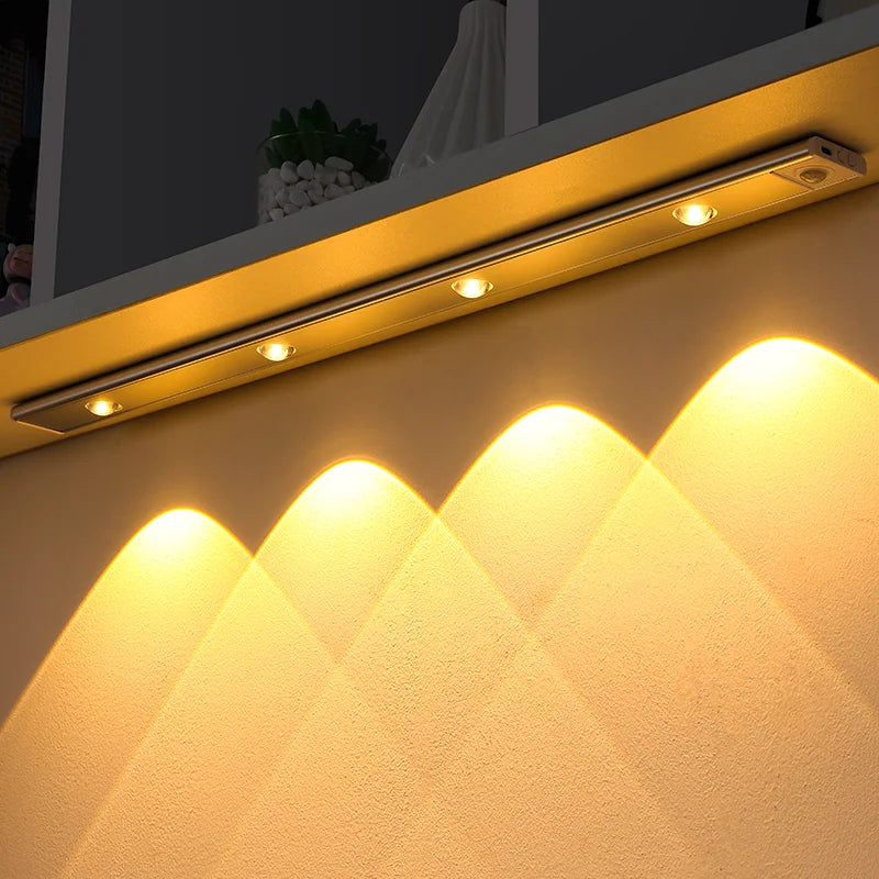 A modern LED light fixture with multiple spotlights illuminates a textured wall surface.