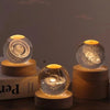 A crystal ball night light with a glowing interior rests on a wooden base.