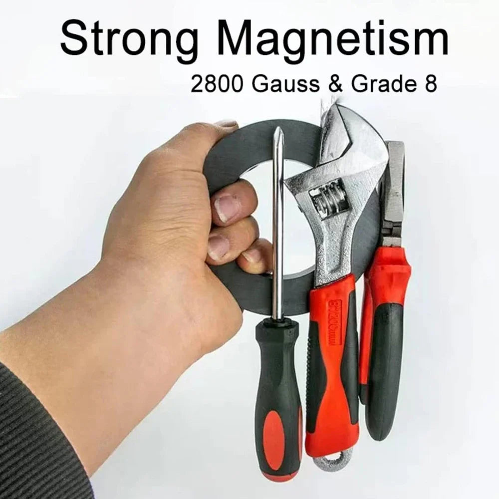 Eine Hand hält einen schwarzen Keramikringmagneten und Werkzeuge, die starke Magnetwirkung für die 8. Klasse der Wissenschaft