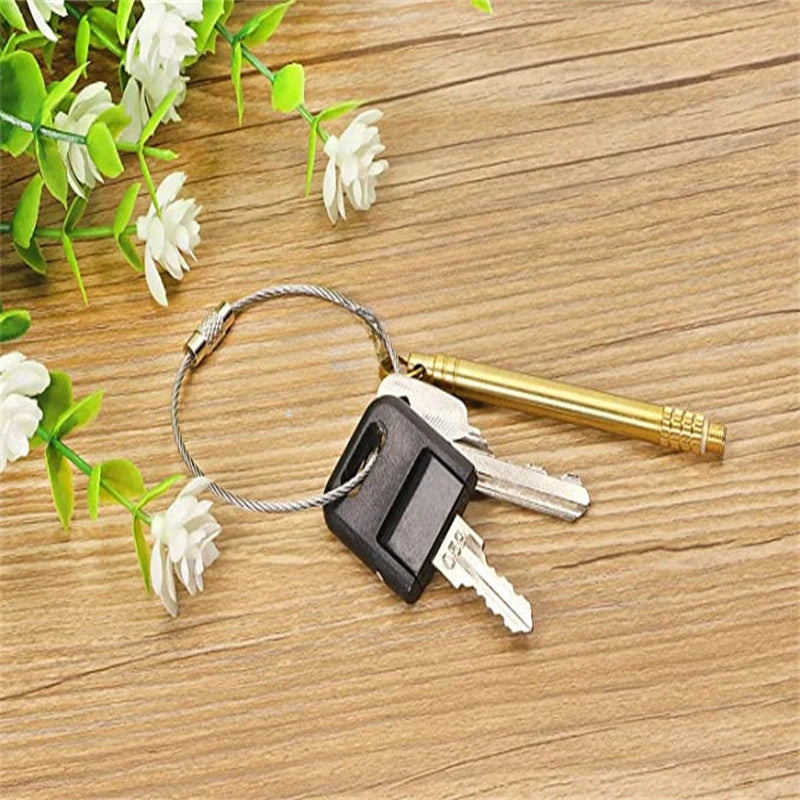 A set of stainless steel wire keychain tags and keys resting on a wooden surface with white flowers.