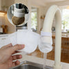 A hand holds a white reusable cotton faucet filter, demonstrating its use for water purification.
