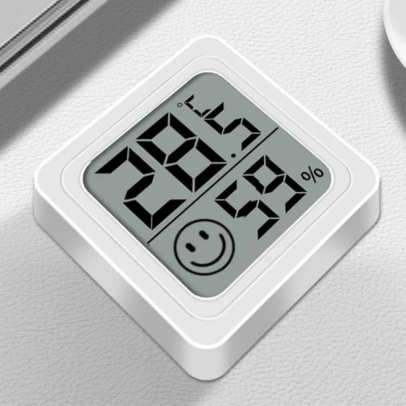 Termómetro digital blanco que muestra una temperatura de 28.5 y un icono de cara sonriente.