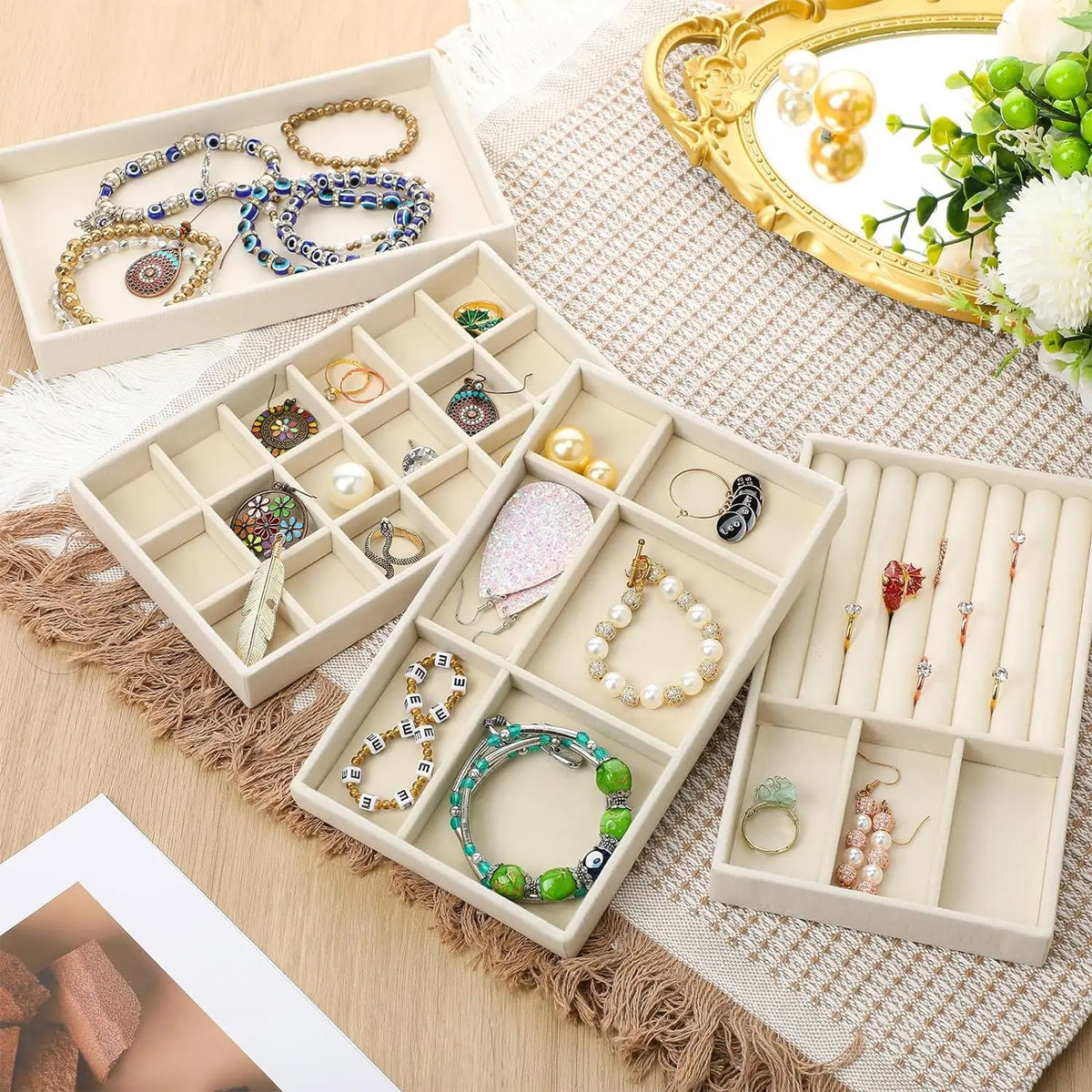 A light wood jewelry storage tray with compartments holding various gold and silver necklaces, rings, and earrings.