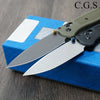 A folding pocket knife with a green handle and silver blades is displayed on a blue box.