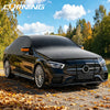 A black Mercedes-Benz sedan with a transparent solar windshield cover parked on an autumn leaf-covered road.