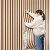 A person is touching a vertical wood grain wall panel with vertical stripes.