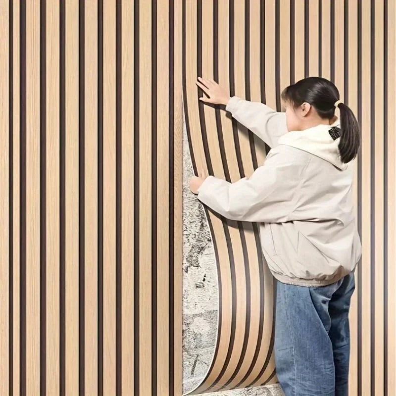 A person is touching a vertical wood grain wall panel with vertical stripes.