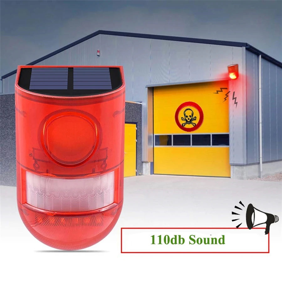 A red solar infrared motion sensor security alarm unit with a lens and a yellow door in the background.