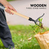 A hand holds a wooden three-stage handle weed puller tool used to remove weeds from the ground.