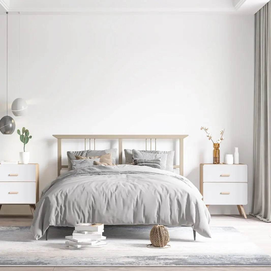 A bedroom setting featuring a bed with gray bedding and light wood furniture against a white wall.