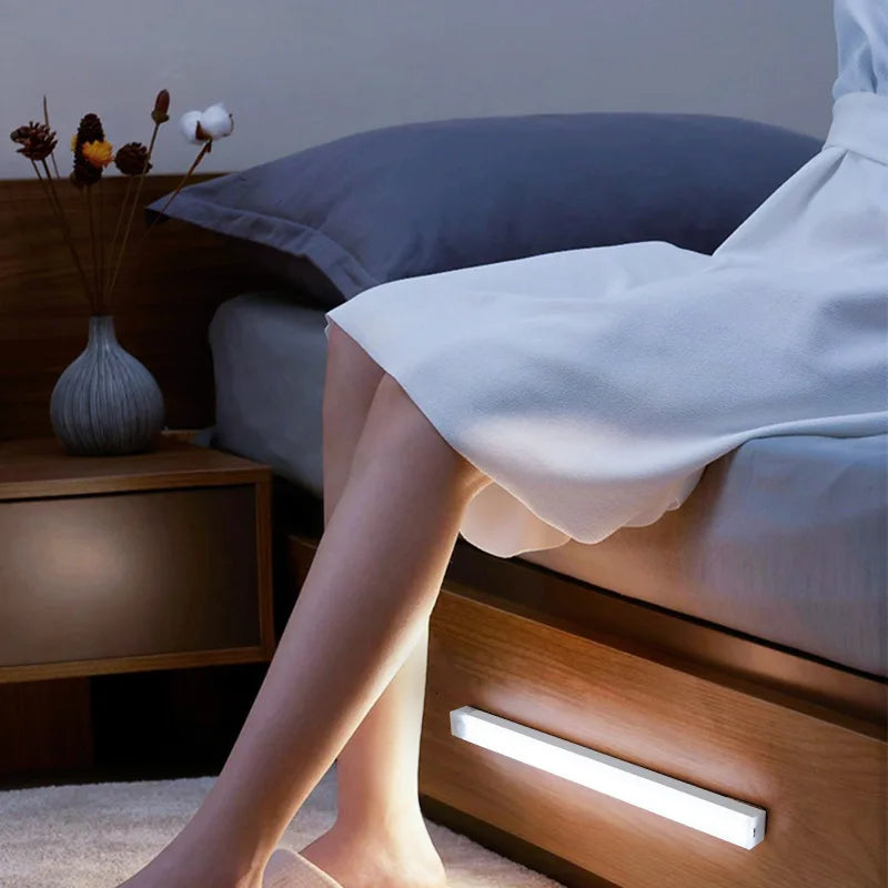 La jambe d'une personne repose sur un cadre de lit en bois avec une lumière LED intégrée, suggérant la sécurité d'un meuble.