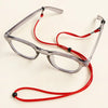 Une paire de lunettes à monture transparente avec un cordon rouge réglable.