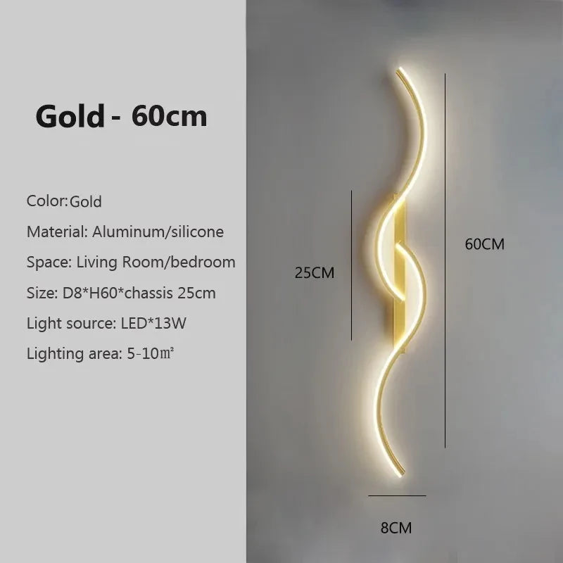 A vertical gold LED wall sconce with a curved design mounted on a light gray wall.