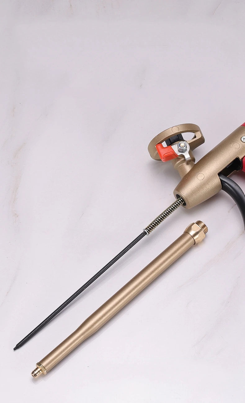 A close-up of a professional PU foam sealant spray gun with a brass body and black hose on a white surface.
