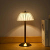 A modern table lamp with a conical glass shade and brass base illuminates a wooden surface.