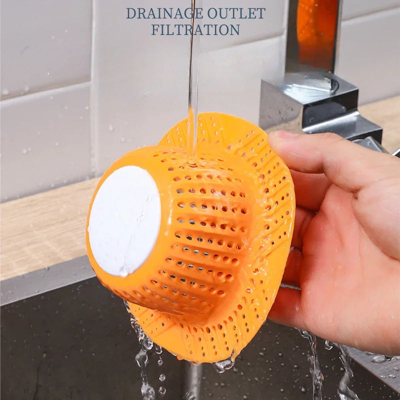 An orange collapsible bathtub drain filter is shown dripping water into a sink.