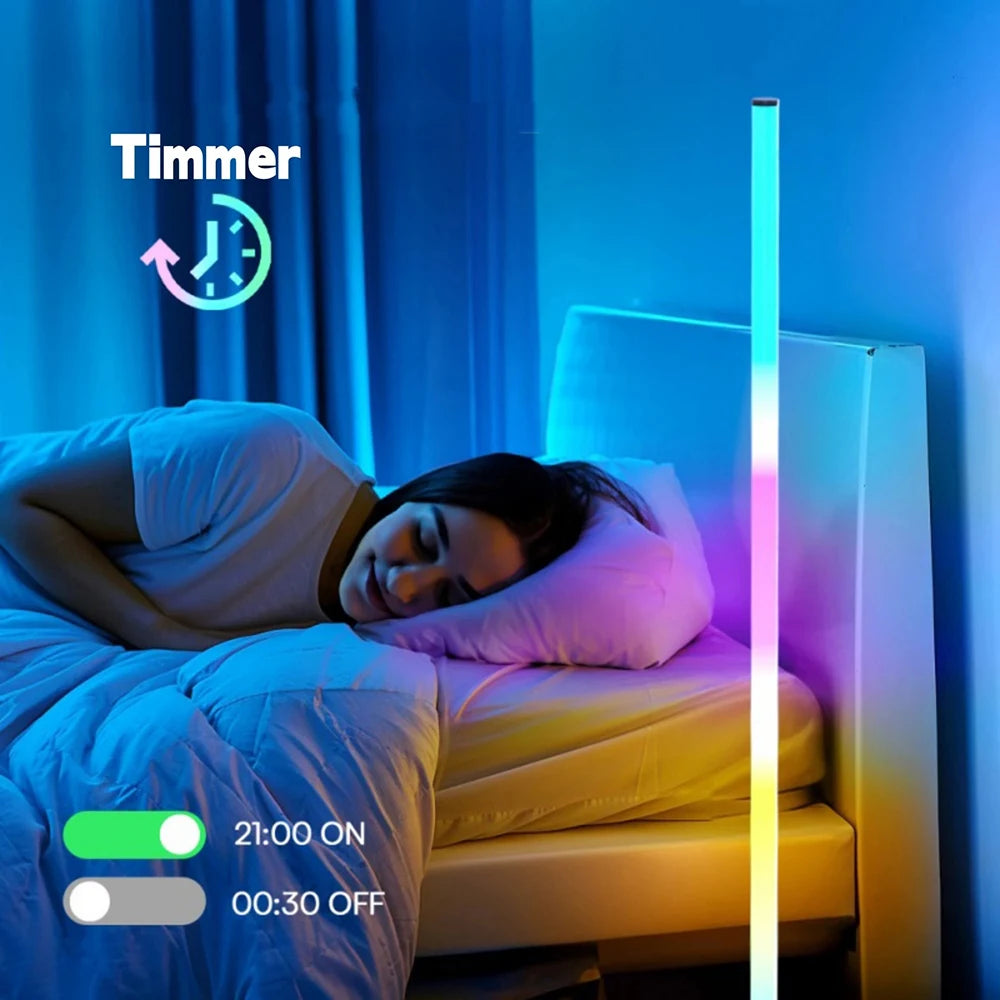A woman sleeping in bed next to an RGB LED corner floor lamp with a timer display set for 21:00 ON and 00:30 OFF.