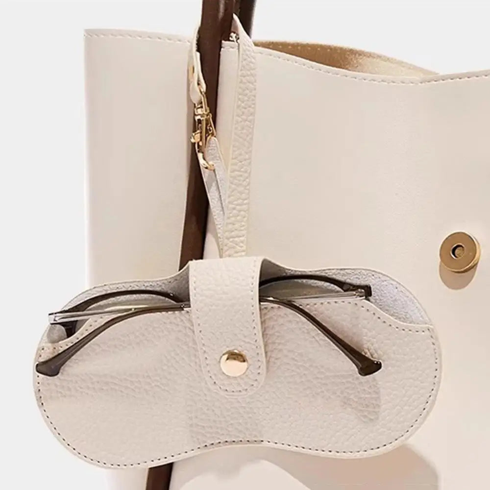 A cream-colored PU leather eyeglasses case with a lychee pattern, featuring a gold-toned clasp and brown strap.