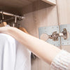 A hand is shown interacting with a cabinet hinge repair kit mounted on a wooden cabinet door.