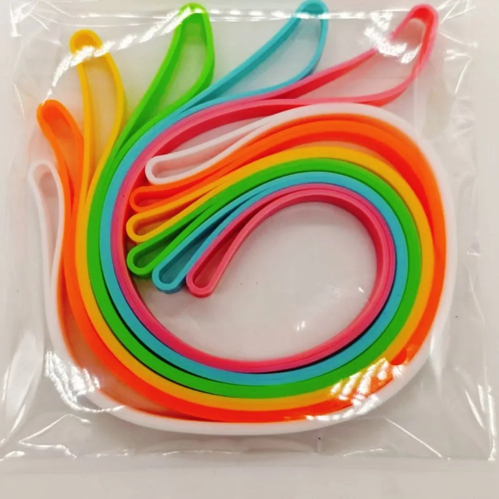 A colorful set of reusable silicone elastic rubber bands in rainbow colors arranged on a white dish.
