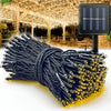 A bundle of black and gold solar powered outdoor LED string lights with wires, displayed in natural light.