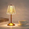 A brass table lamp with a textured glass shade illuminates a white cup on a light surface.