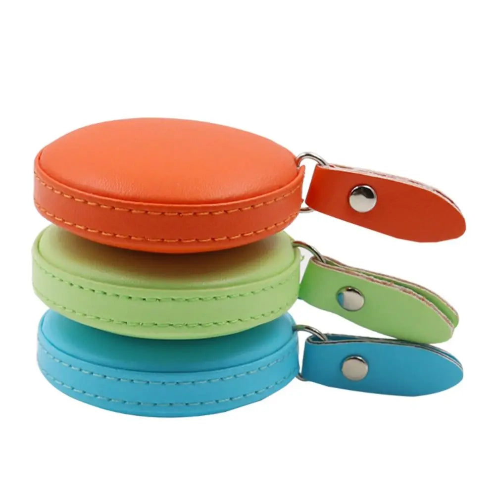 Three colored retractable dual scale measuring tapes stacked and laid out.