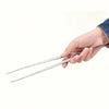 A hand holds a pair of precision dual-tip tweezers with slender metal tips.