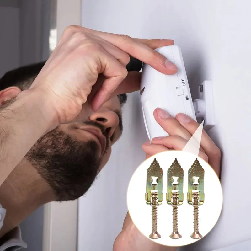 A hand is installing a self-drilling drywall anchor into a wall, showing the anchor and its screw mechanism.