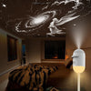 A white Galaxy Star Projector night light illuminates a bedroom ceiling with a swirling galaxy and an angel silhouette.