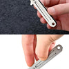 A hand holds a stainless steel folding keychain knife against a brown cardboard box.
