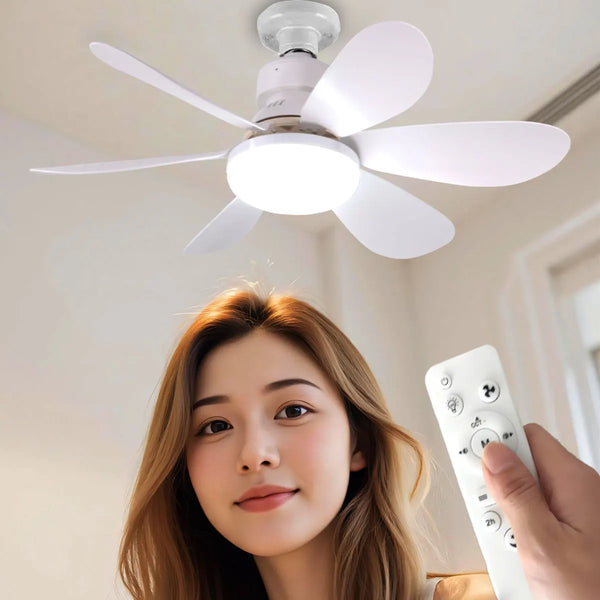 A woman is holding a white remote control for an LED ceiling fan with a light and blades visible above her.