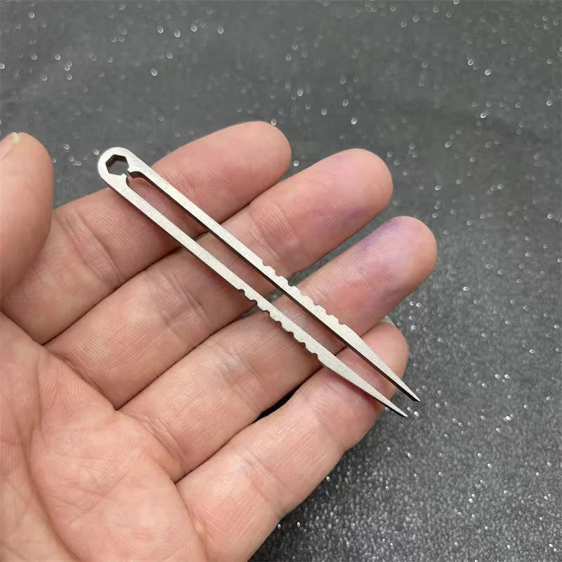A hand holds a pair of silver titanium clip tweezers with fine points for precision use.