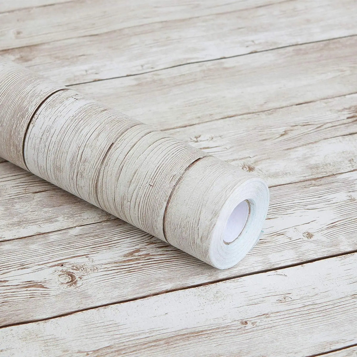 A roll of white self-adhesive wall stickers resting on a light wooden surface.