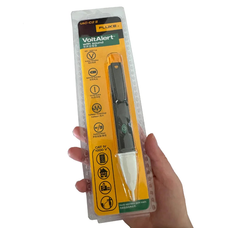 A hand holds a Fluke VoltAlert non-contact AC voltage detector pen with yellow and black casing.